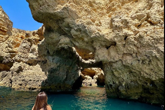 a woman sitting on a rock next to water